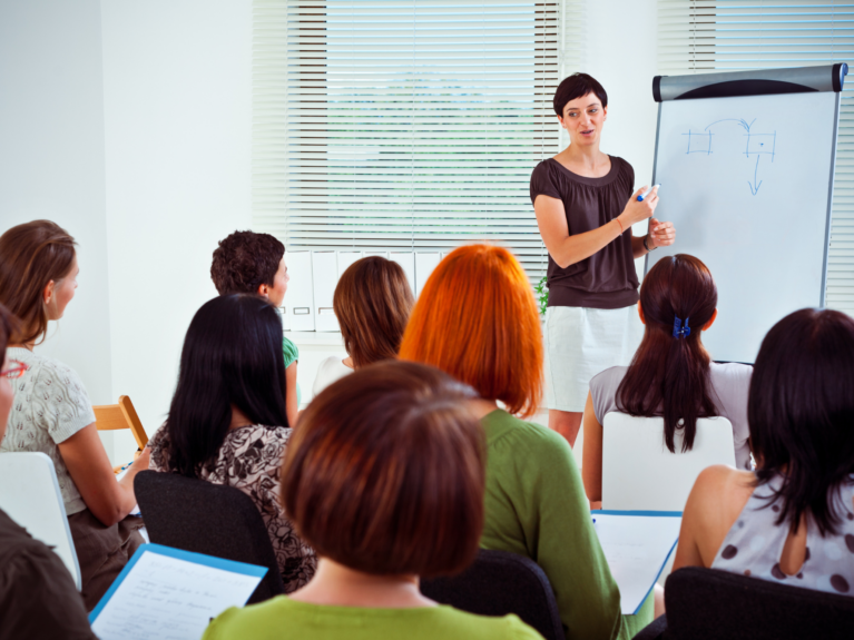 Educator giving training to other educators in a white classroom