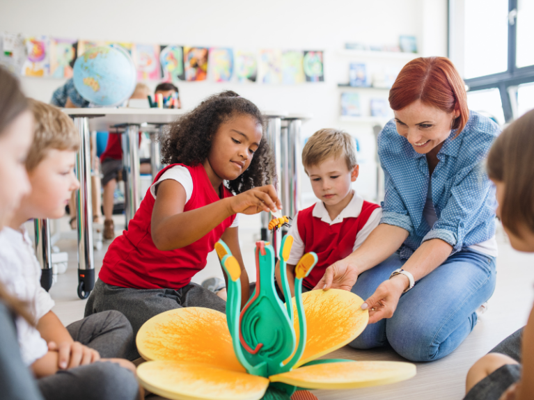 Caucasian Teacher playing with a flower toy with young children